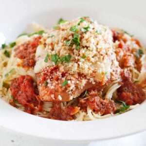 Slow-cooker chicken parmesan over pasta in a white bowl