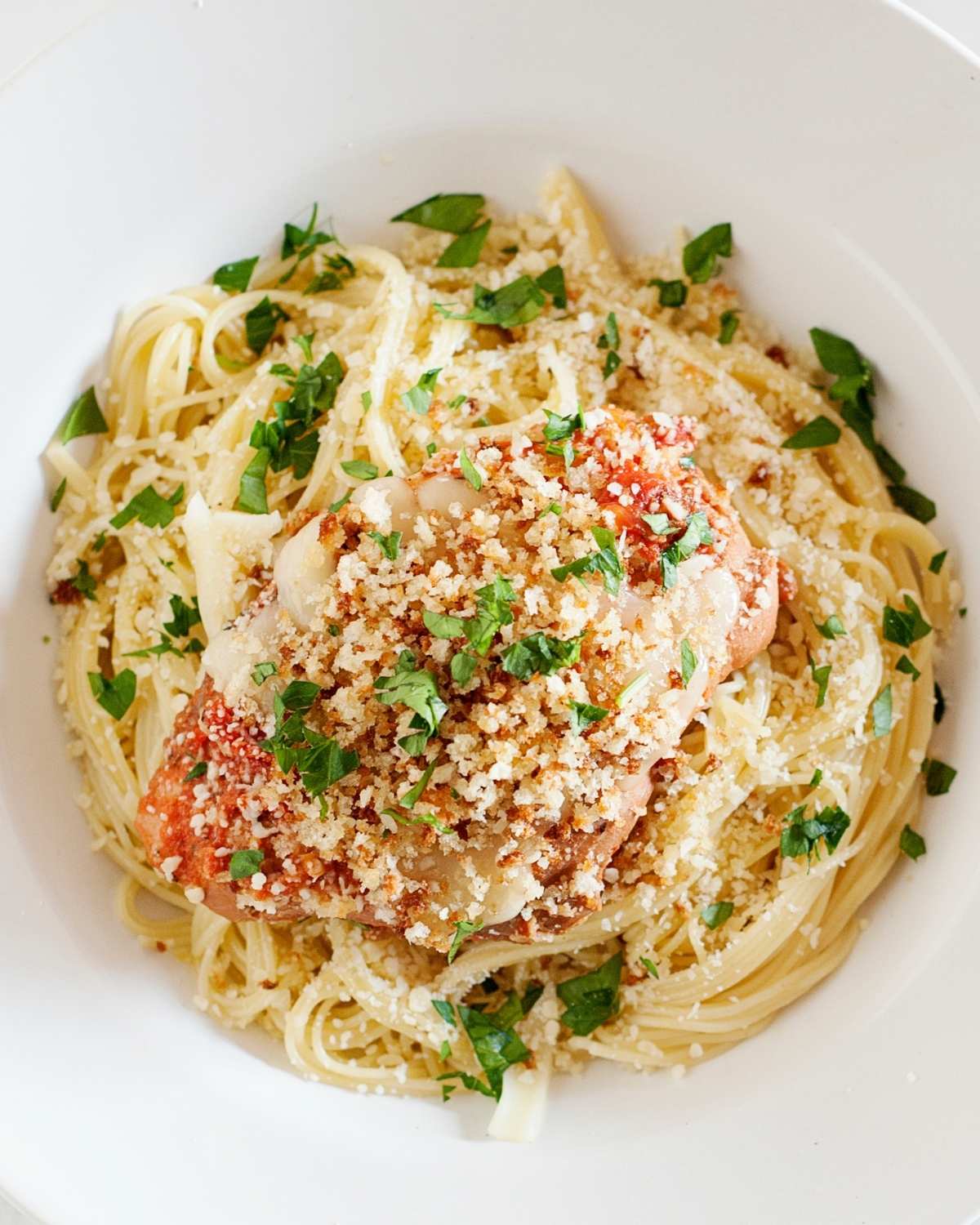 slow cooker chicken parmesan over pasta in a white bowl