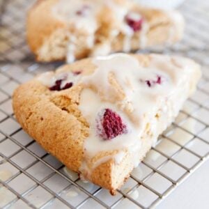 two raspberry scones with glaze over a cooling rack