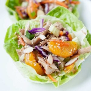 image: closeup of white plate with chopsticks, and a lettuce cup filled with asian chicken salad