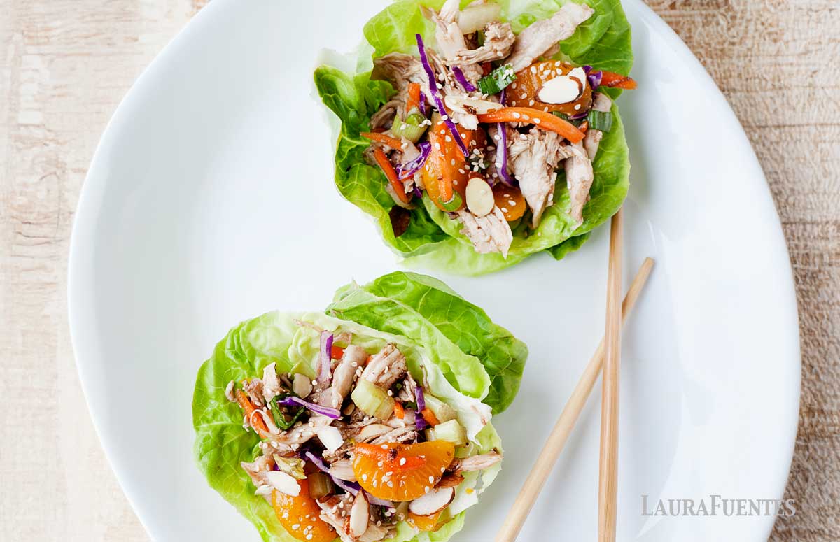 image: white plate with chopsticks, and two lettuce cups filled with asian chicken salad