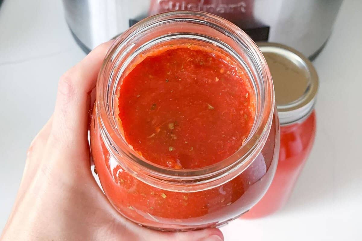a hand showing a jar of tomato sauce