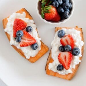 sweet potato toast topped with cottage cheese and berries, and a small bowl of berries on the side
