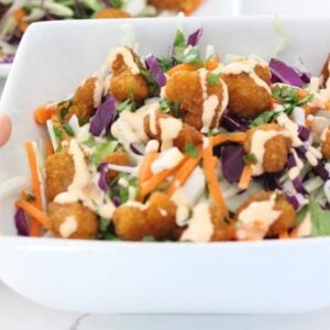 a bowl with popcorn shrimp salad with dressing