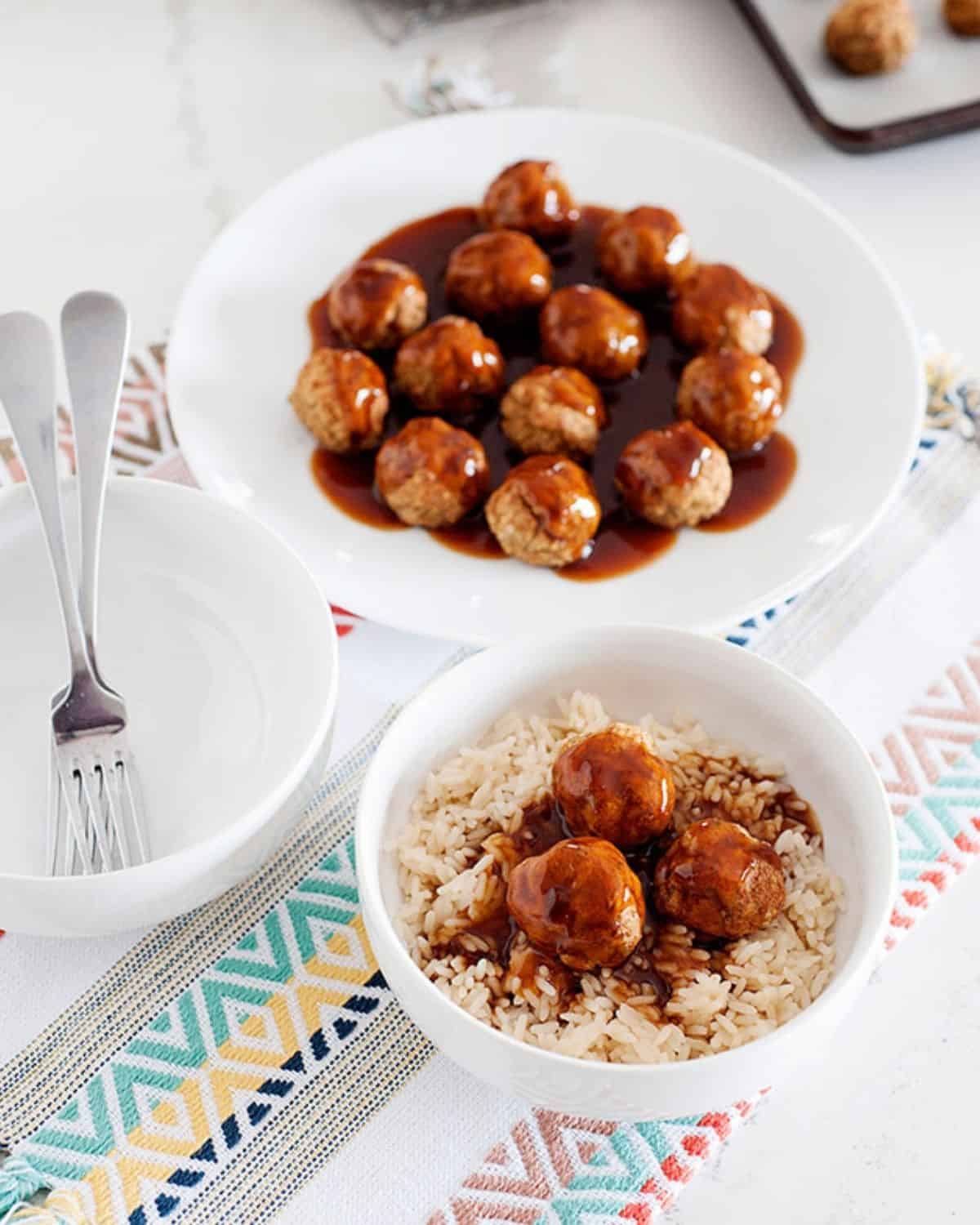 bowl of sweet and sour meatballs served over rice and a another bowl behind with meatballs