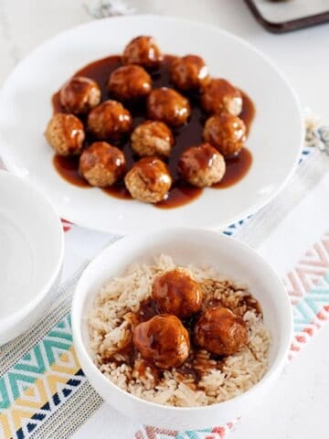 bowl of sweet and sour meatballs served over rice and a another bowl behind with meatballs