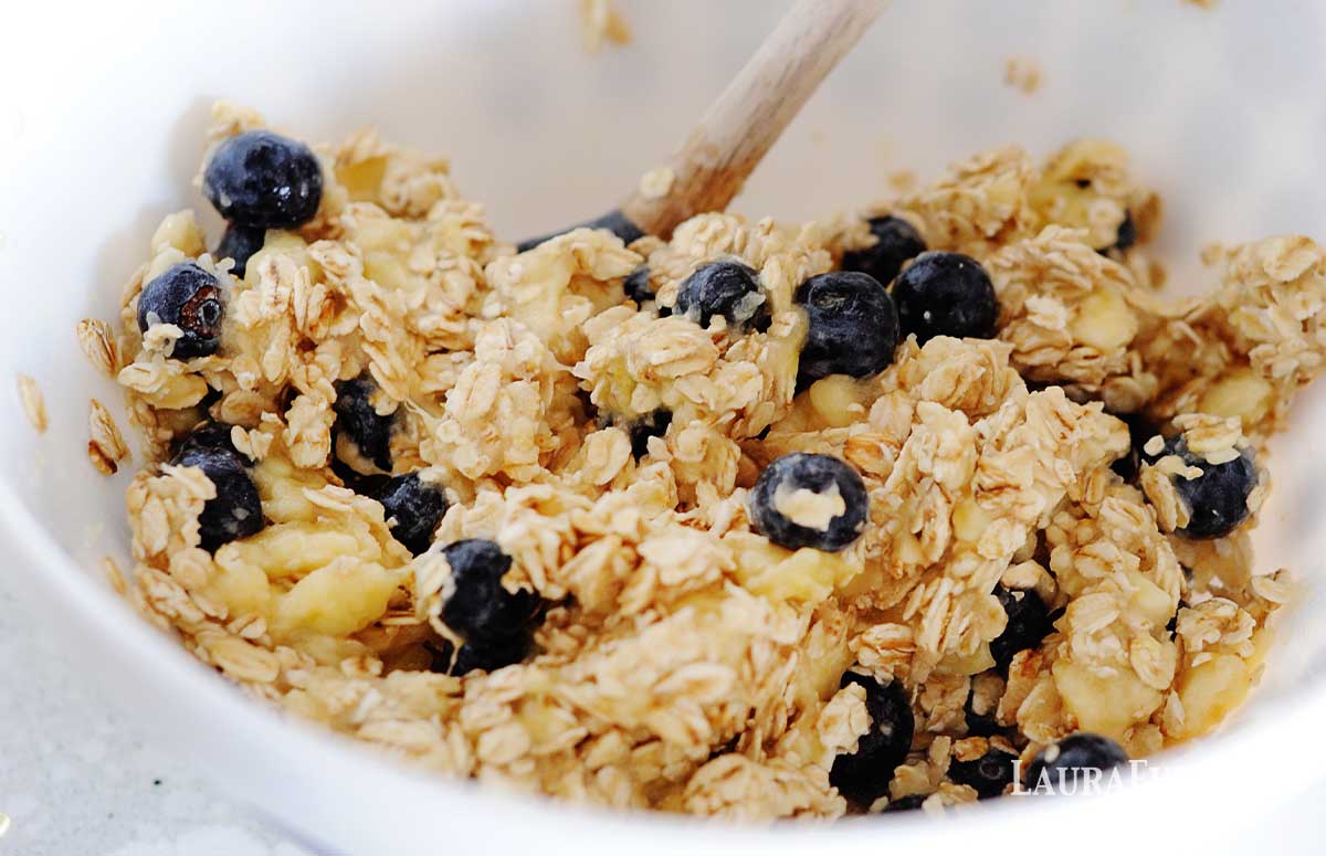 oats, bananas and blueberries mixing together in a batter bowl