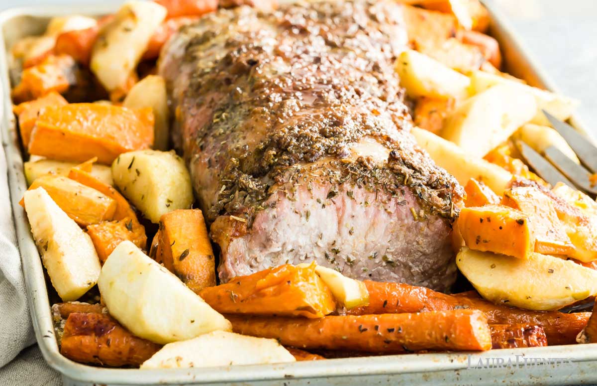 easy sheet pan pork roast with a brown sugar and dijon glaze with sweet potatoes and carrots on a baking tray