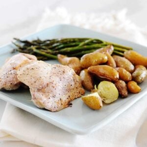 baked chicken, asparagus and potatoes arranged on a square blue plate for dinner
