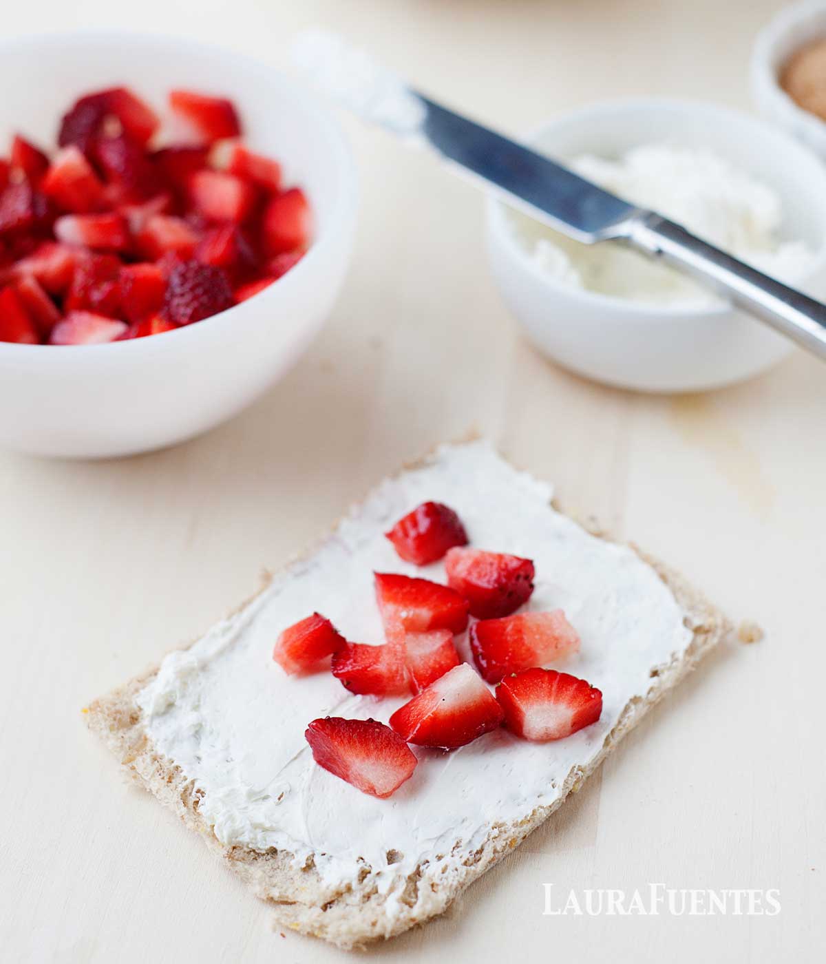 making of strawberry french toast roll ups: a slice of bread with cream and strawberry slices on top