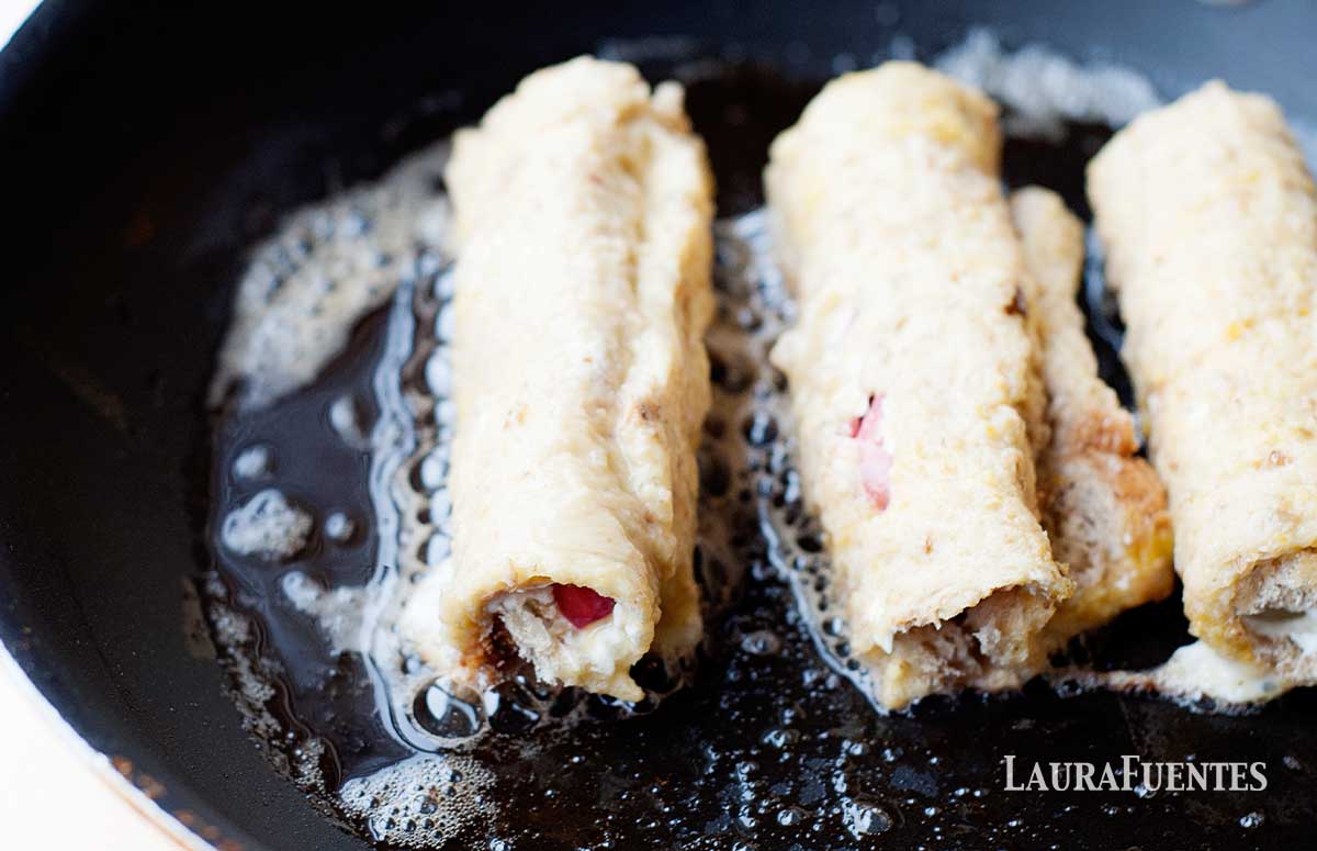 frying strawberry french toast roll ups in a pan