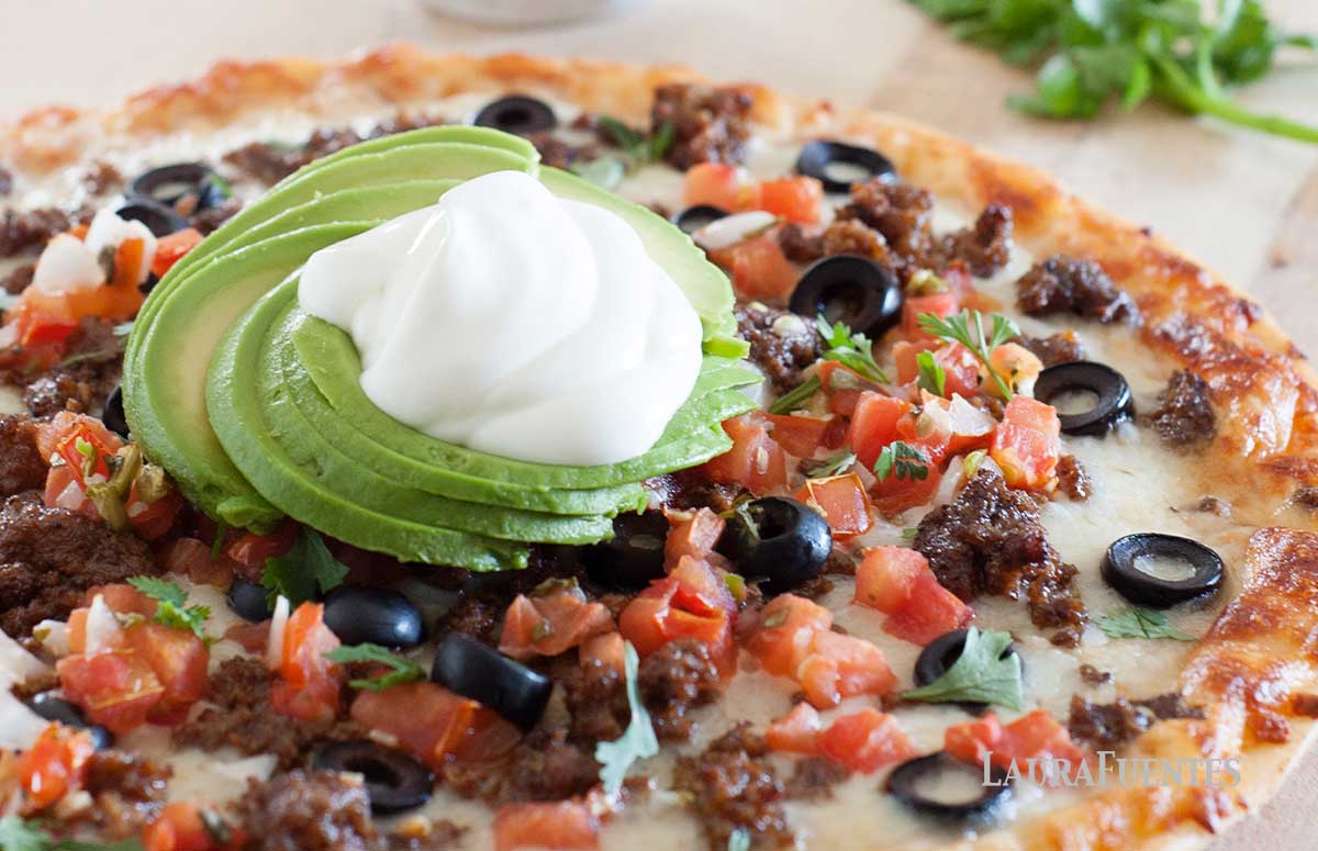 taco pizza with avocado and sour cream on top