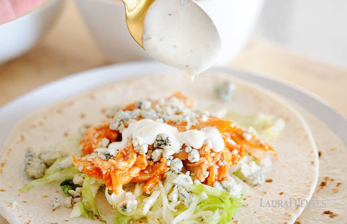 slow cooker buffalo chicken tacos which is poured with ranch dressing