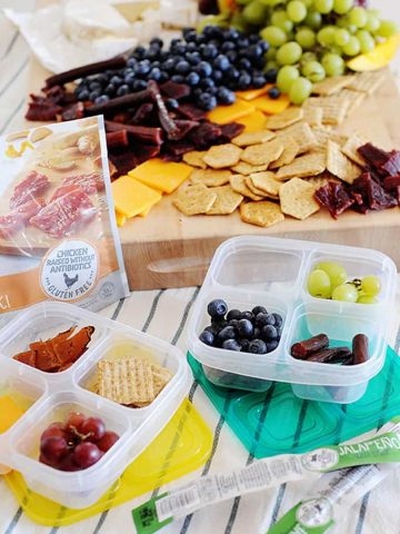 Snack board with fruit, cheese, and premium chicken cuts, jalapeno beef sticks, and crackers