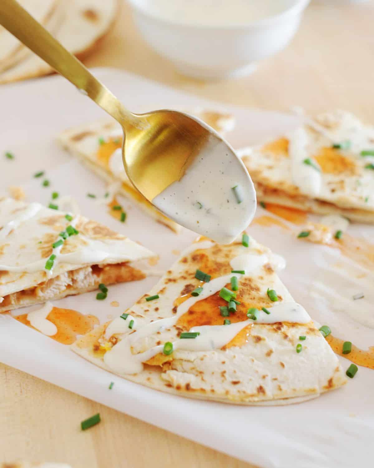 drizziling Ranch over Buffalo chicken quesadillas