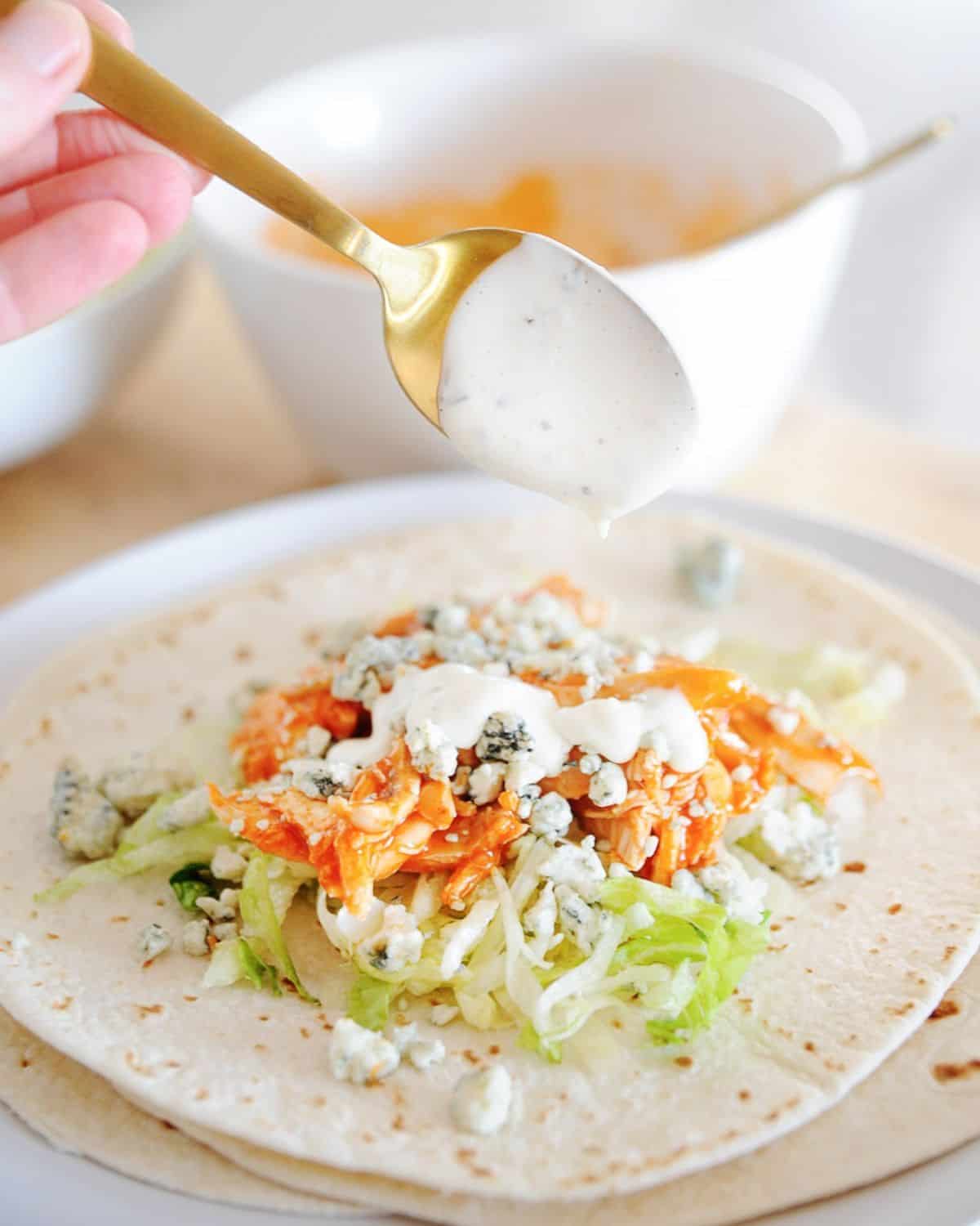 Ranch dressing being drizzled over a Buffalo chicken taco