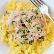 bed of spaghetti squash on a white plate with chicken in garlic butter on top