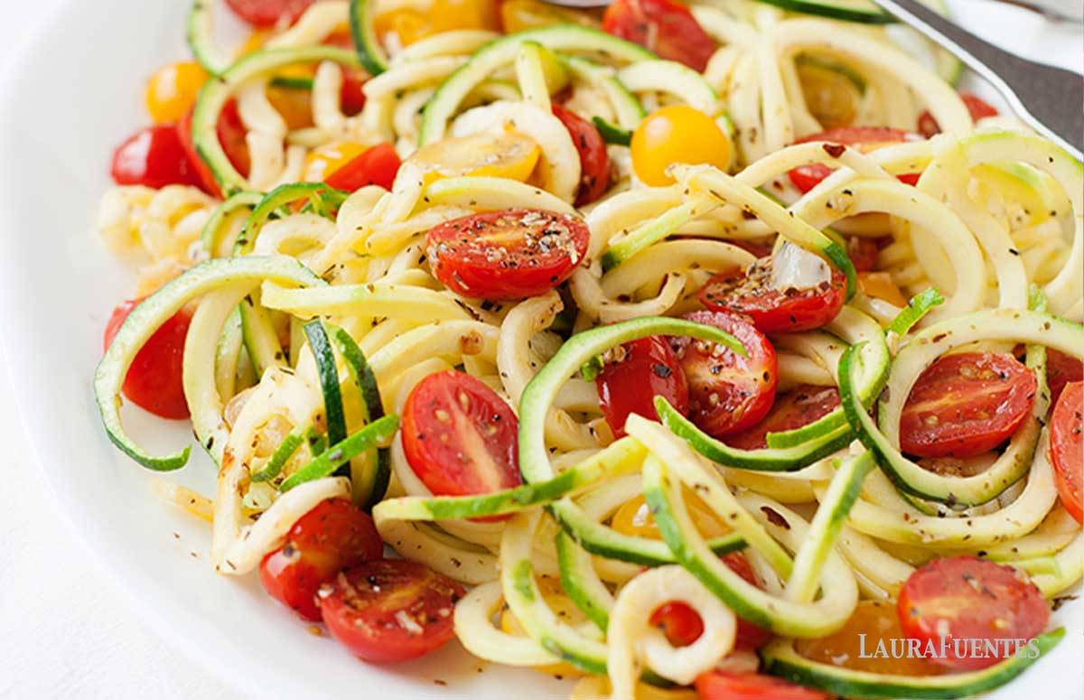 zucchini noodles on a plate with spices and halved tomatoes