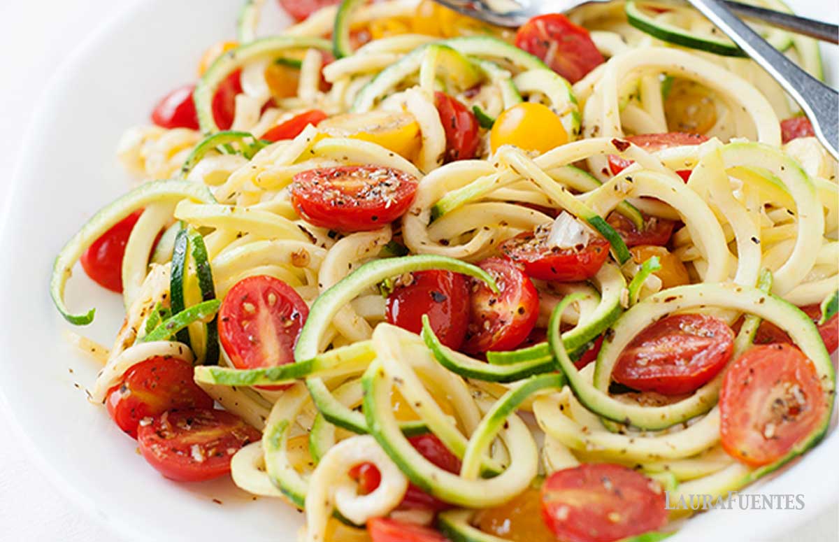 zucchini noodles on a plate with spices and halved tomatoes