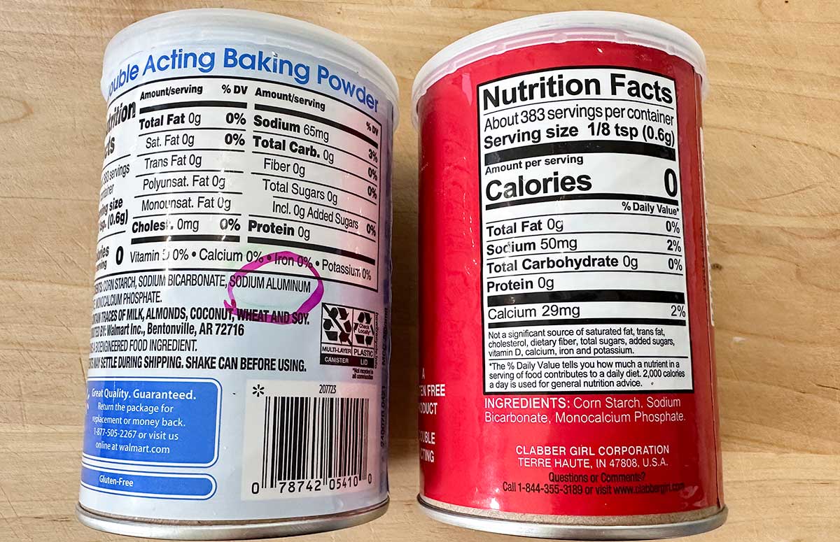 two cans of baking powder for pancakes. One contains aluminum in the ingredients (left) the other can does not (right)