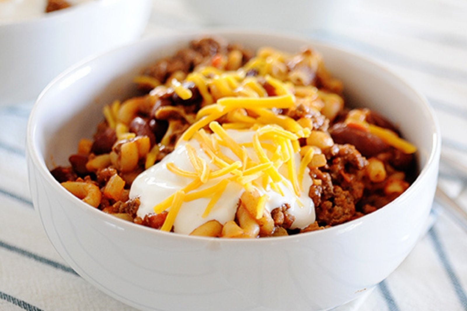 a bowl of chili mac topped with sour cream and chees