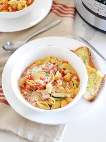 a white bowl with minestrone soup, bread on the side, and a instant pot behind