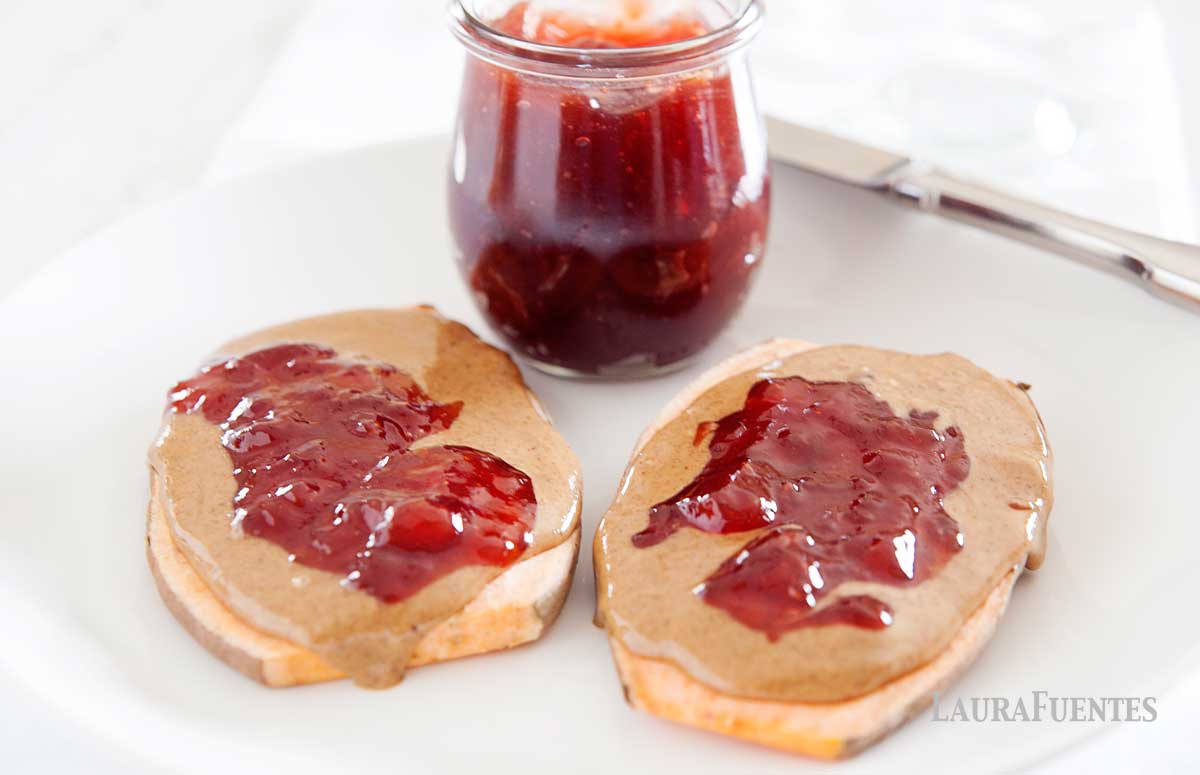image: two slices of sweet potato toast on a white plate next to a jar of strawberry jelly 