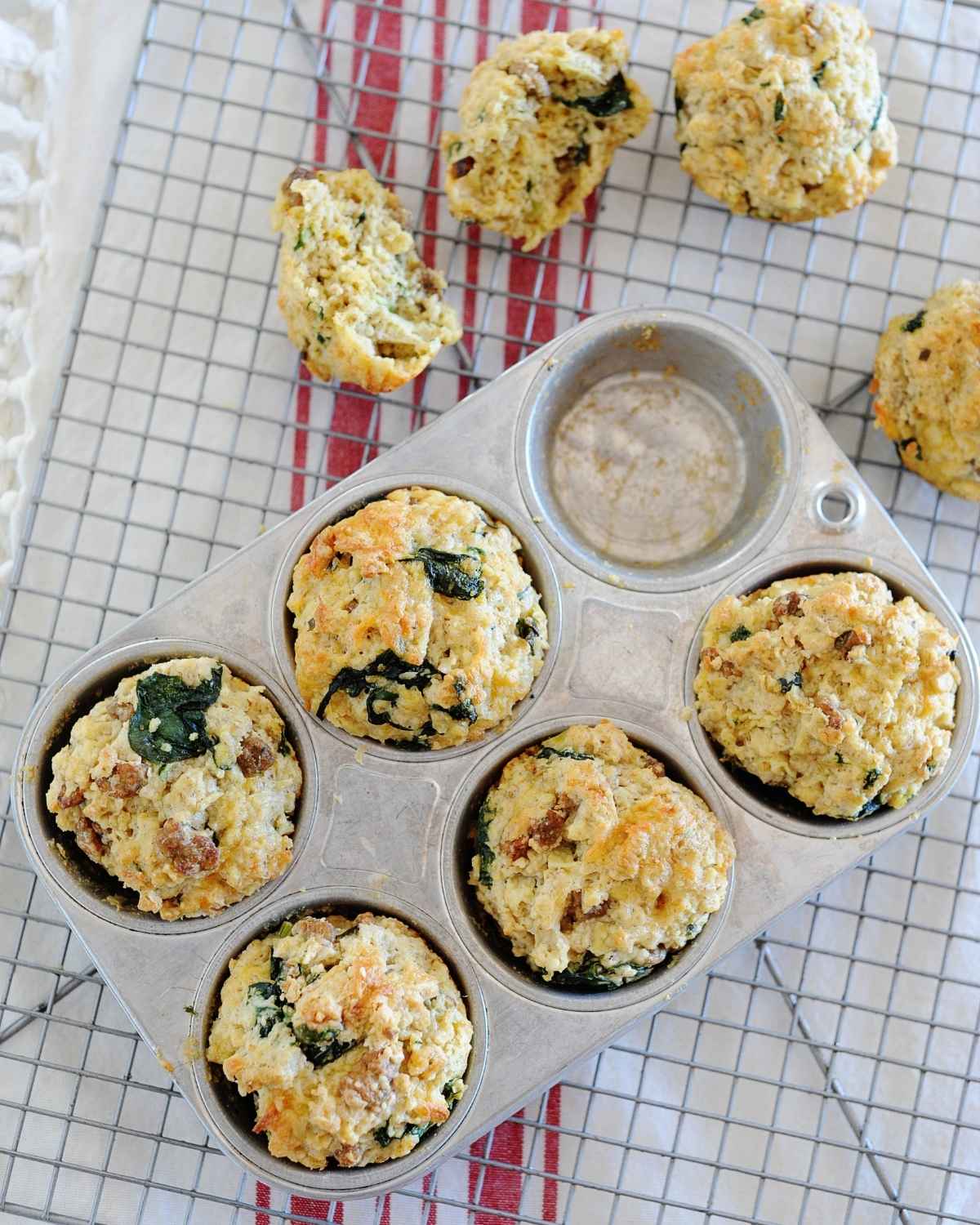a muffin pan with five savory sausage muffins and two more on the side