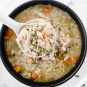 large pot of chicken and rice soup with a large spoonful of soup