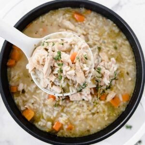 large pot of chicken and rice soup with a large spoonful of soup