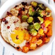 a bowl of oatmeal with roasted vegetables and a fried egg