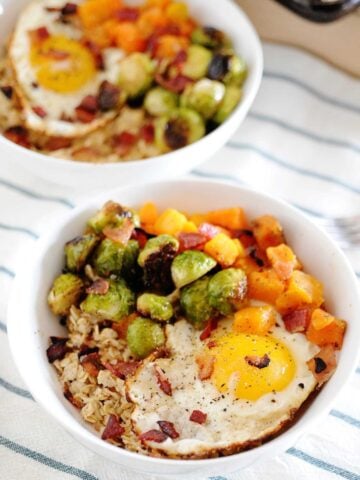 two bowls of oatmeal with roasted vegetables and a fried egg