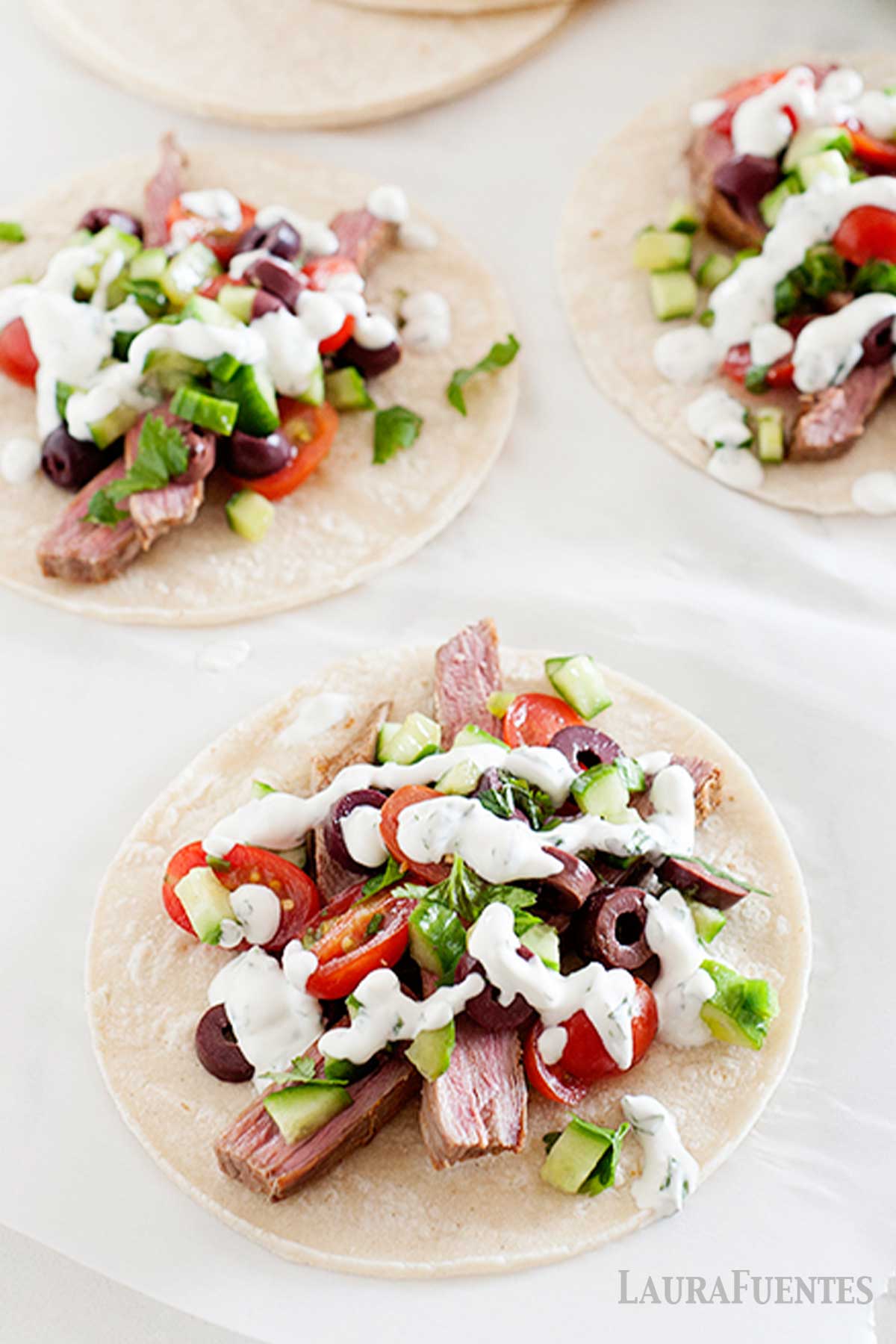 greek tacos with cucumber tacos on a plate with more tacos in the background