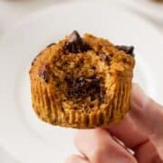 a hand showing the texture of a pumpkin protein muffin