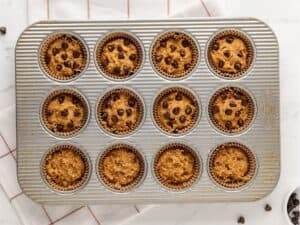 muffin pan with pumpkin protein muffin batter topped with chocolate chips