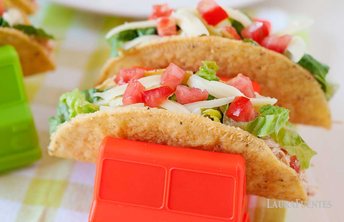 salsa chicken tacos in truck shaped taco holders and taco shells in the bachground