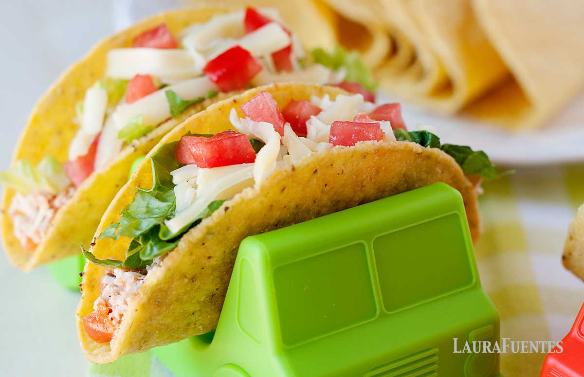 salsa chicken tacos in truck shaped taco holders and taco shells in the bachground