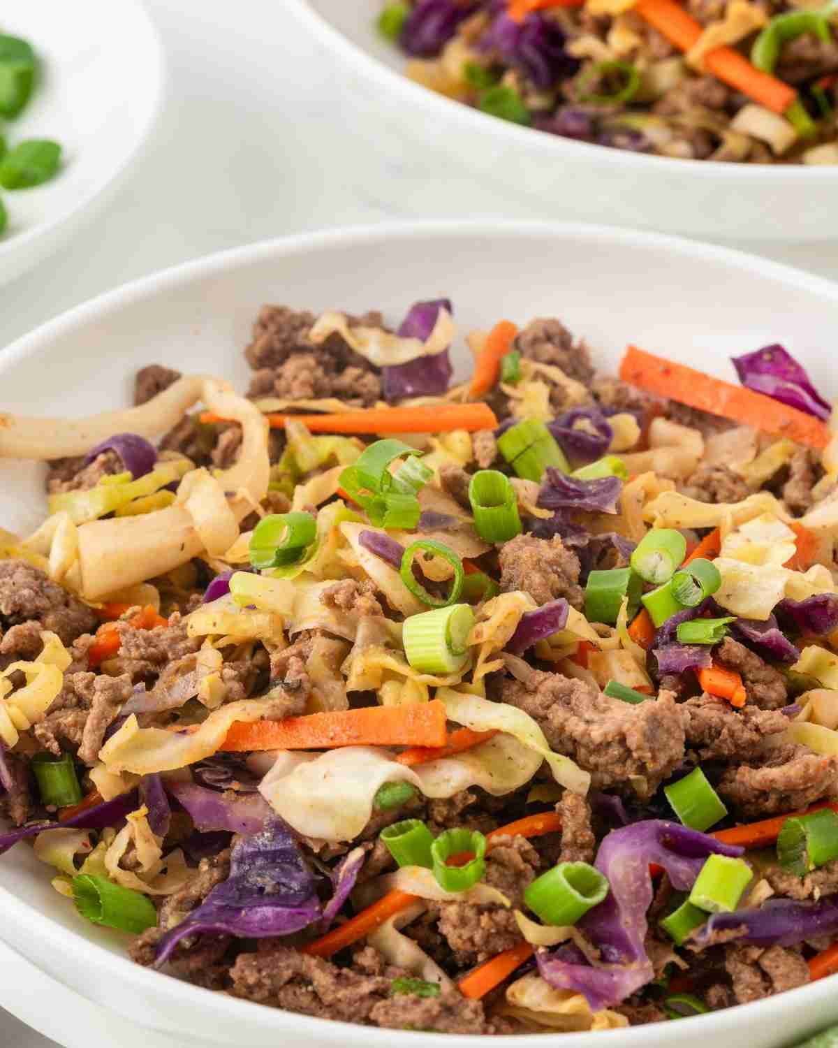 overhead view of a bowl with deconstructed eggroll containing cabbage, veggies, and meat.