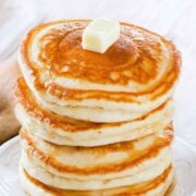 stack of golden, fluffy gluten-free pancakes topped with butter on a plate