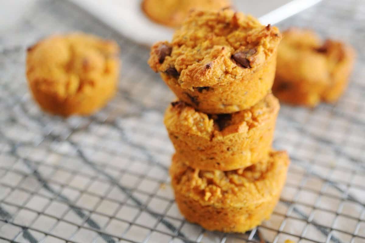 three pumpkin protein muffins with chocolate chips stacked