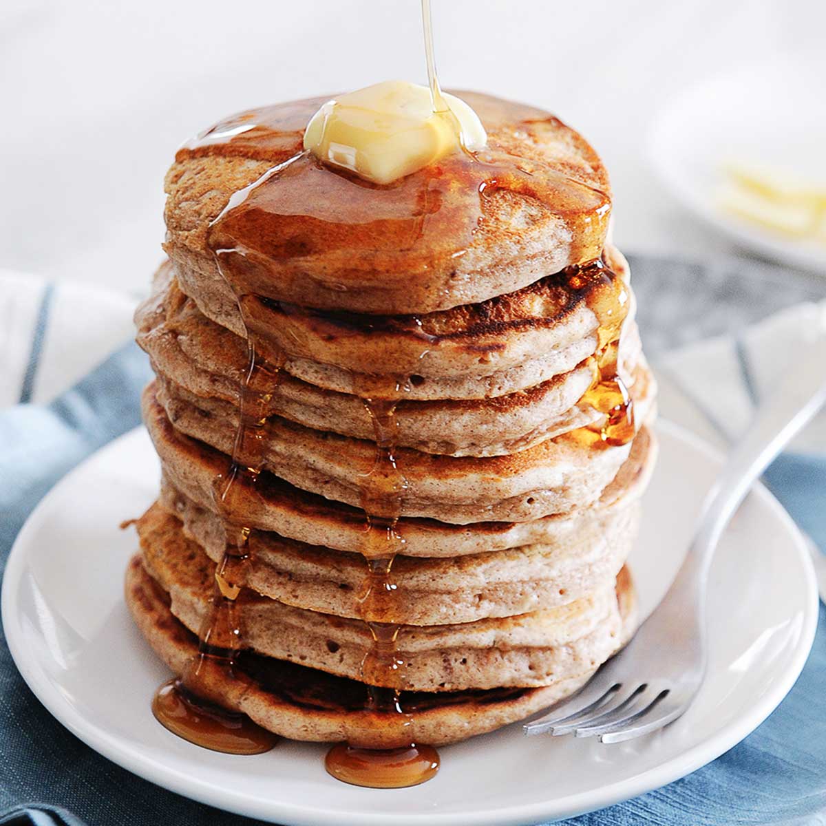 large stack of cinnamon pancakes topped with butter and syrup