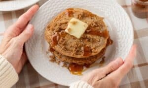 two hands grabbing a plate of the best cinnamon pancakes