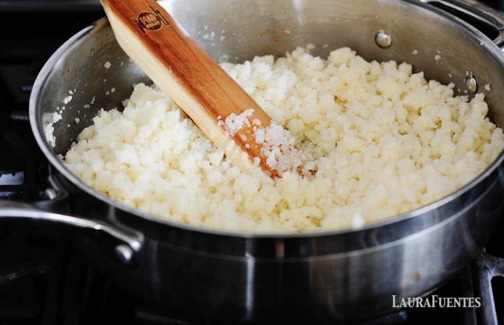 image: Step 1 cooking low-carb burrito bowls, making the cauliflower rice on the stove in a large skillet.