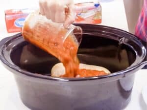 pouring salsa over chicken in the slow cooker bowl