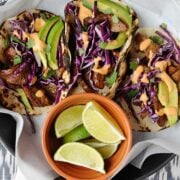 Korean beef tacos on a plate with lime wedges
