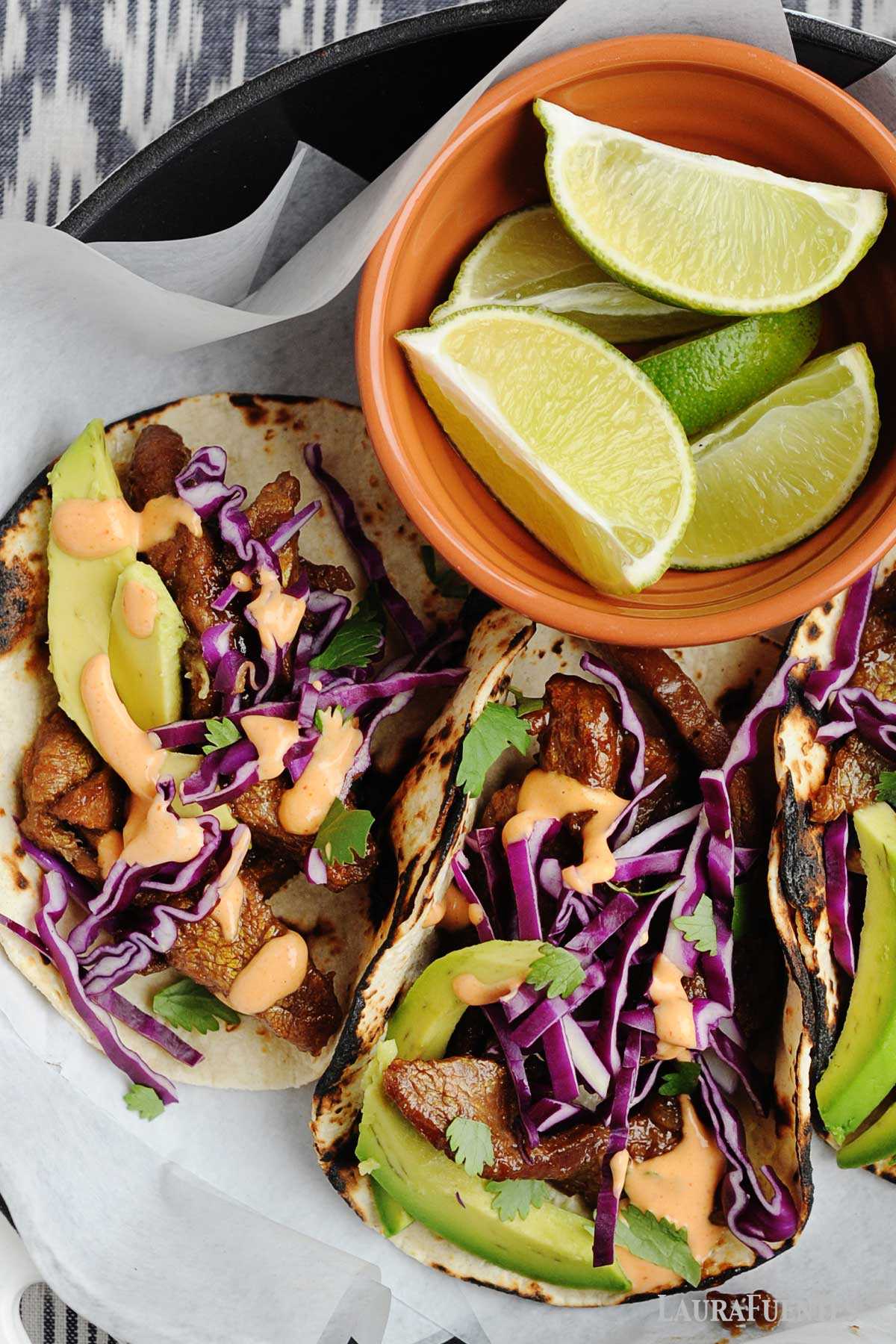 Korean beef tacos on a plate with lime wedges