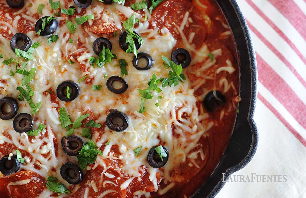 image: skillet with chicken, red sauce, pepperonis, sliced olives and grated cheese