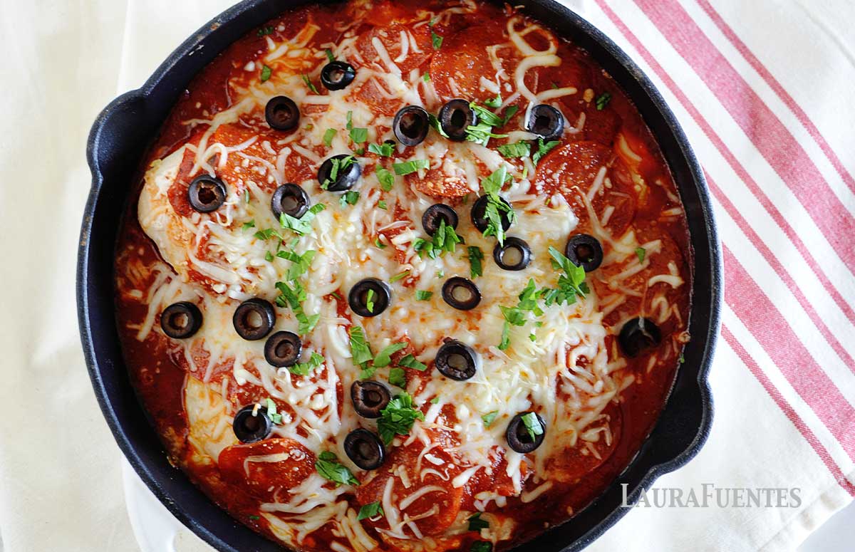 image: skillet with chicken, red sauce, pepperonis, sliced olives and grated cheese