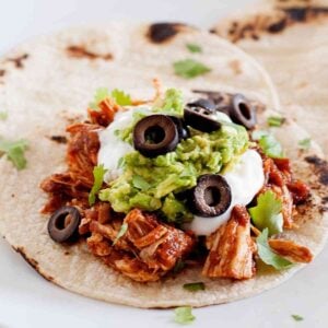 shredded chicken enchilada taco topped with sour cream and guacamole