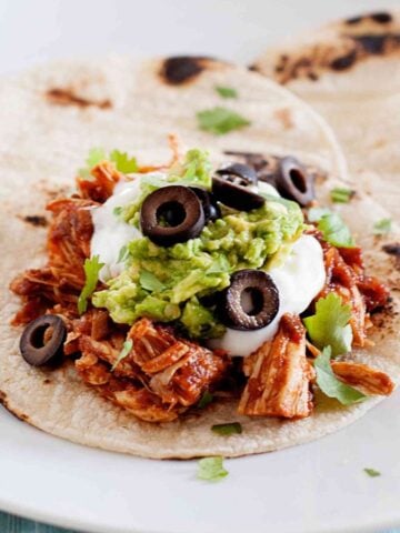 shredded chicken enchilada taco topped with sour cream and guacamole